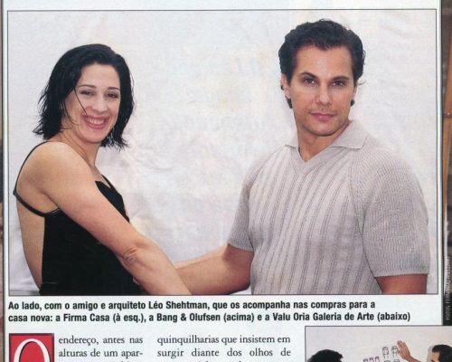 Foto do casal Cláudia Raia e Edson Celulari na Galeria Valu Oria, em São Paulo, ao lado de obra e segurando papel com imagem das obras Cadeiras e Bancos, “Casa nova, paz e bom gosto”, Chiques e Famosos, set. / out. 1998